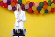 Na żółtym tle sceny amfiteatru wiszą kolorowe balony. Na scenie występuje wokalistka z MDK…