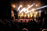 Widok ogólny na amfiteatr w czasie koncertu Rock Noc. Tłumy publiczności oraz oświetlona scena, a…