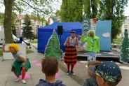 Widok na aktorkę i dwóch aktorów podczas spektaklu. W tle dekoracje.