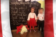 Dziewczynka i chłopczyk pomiędzy biało-czerwonymi flagami