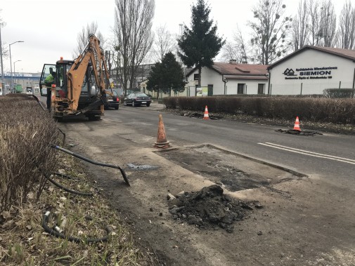Pozimowy remont ulicy Wyzwolenia, na pierwszym planie jest naprawiany ubytek w jezdni, w tle stoi…