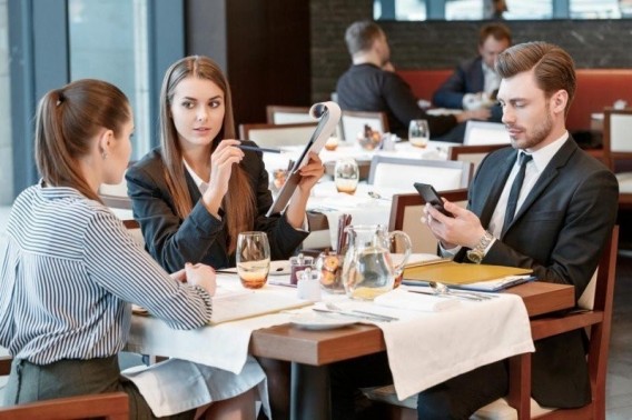 Przy stole siedzące dwie młode kobiety i mężczyzna