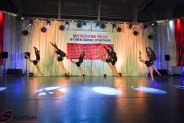 7 cheerleaderek w czarnych strojach podczas tańca na  tle flagi Mistrzostw Polski w Cheerleadingu…