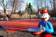 Widok na skwer; na pierwszym planie poidełko w postaci bajkowego "ludzika" w niebieskiej koszuli…