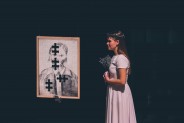 Młoda dziewczyna w białej sukiennce z skormnym bukietem.