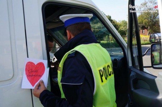 Policjant wręczający kierowcy laurkę