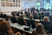 Młodzi sportowcy wraz z trenerami siedzą w dużej sali ratusza. Na drugim planie gospodarze…