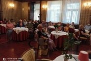 Publiczność podczas wernisażu Jolanty Skrzypczyk, ok. 25 siedzących osób, widok ogólny sali, w…