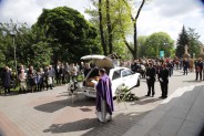 Ksiądz modlący się przed karawanem pogrzebowym w trakcie uroczystości