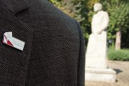 Symboliczna przypinka upamiętniająca 100-lecie Powstań Śląskich. W tle pomnik Wojciecha Korfantego.