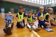 Dzieci siedzą na parkiecie i oglądają swoje nowe stroje