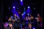 Na scenie SCK zespół Arkadia Band. Dwoje mężczyzn gra na gitarze i akordeonie, za nimi tańczą…