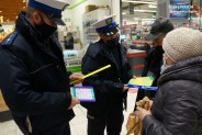 Policjanci wręczający laurkę starszej pani