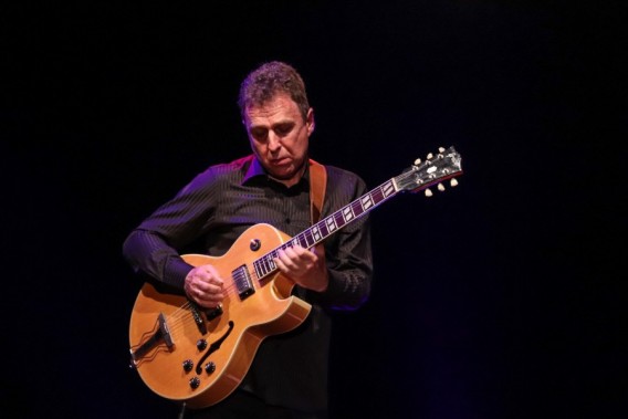 Zbliżenie na sylwetkę Bohdana Lizonia w ciemnej koszuli, grającego na gitarze