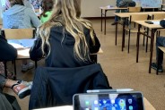 Nauczyciel przy tablicy i siedzący w ławkach uczniowie
