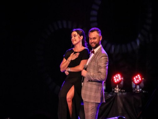 Na scenie śpiewak Tomasz Białek i prowadząca koncert Barbara Pakura-Brzoska tańczą razem. On w…