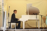 Pianista Rafał Gudyka przy białym fortepianie na tarasie SCK Zameczek