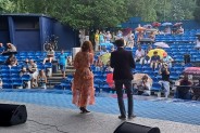 Widok z tyłu sceny na widownię z siedzącą pod parasolami publicznością