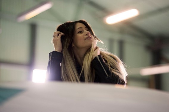 Na zdjęciu Joanna Dolata w skórzanej kurtce, oparta o blat z ręką we włosach