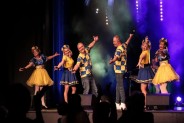 Na scenie, na tle niebieskich świateł stoi zespół Happy Jędrowski Show czyli cztery panie i dwóch…