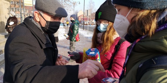 Mężczyzna wrzucający pieniądze do puszki jednej z dwóch dziewczynek