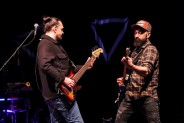 Zbliżenie na basistę i gitarzystę zespołu Macieja Balcara któzy grają na gitarach odwróceni…