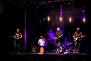 Widok na scenę SCK- Bytków, gdzie w niebieskim świetle scenicznym stoi zespół Macieja Balcara.…