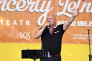 Piotr Herdzina stoi na scenie Amfiteatru Miejskiego nawołując publikę do czynnej zabawy podczas…