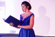 Lucyna Jarząbek ubrana w niebieską suknię trzyma w ręku okładkę