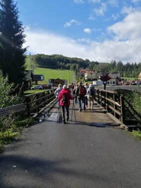 Biorący udział w marszu idą z kijkami przez most