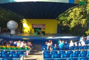 Panorama amfteatru z publicznością i całą sceną. Na scenie widoczne reklamy letnich koncertów…