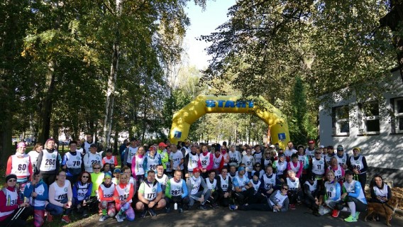 Zdjęcie grupowe 200 uczestników  Biegu Jesieni i Nordic Walking w Parku Pszczelnik na tle żółtej…