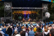Widok od tyłu na widownię i scenę amfiteatru podczas Pikniku Country. Na scenie trwa koncert…