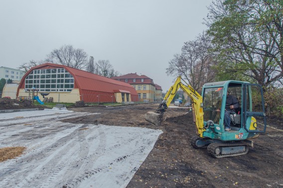 Teren przygotowywany pod budowę boiska. Po prawej stronie koparka wykonująca roboty ziemne.
