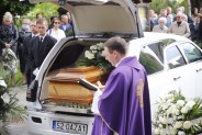 Ksiądz modlący się przed karawanem pogrzebowym w trakcie uroczystości