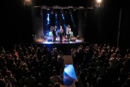 Widok z góry na salę koncertową pełną ludzi bijących brawo po koncercie Mikromusic. Na scenie…