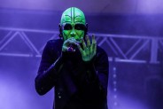 Wokalista zespołu Transgresja w czarnym stroju, z twarzą pomalowaną żółtą, fluorescencyjną farbą