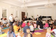 Na Sali Lustrzanej uczestnicy siedzacy na podłodze wśród nich artyści grający na instrumentach