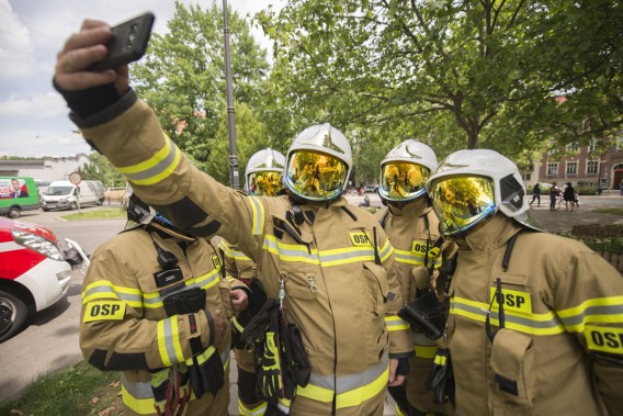 Druhowie z siemianowickiej OSP ubrani w nowe stroje typu NOMEX, robią sobie "selfie". W tle Rynek…
