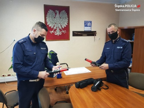 Dwaj policjanci prezentują urządzenia do badania stanu trzeźwości