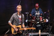 Na pierwszym planie gitarzysta i wokalista zespołu Alabama Band. Śpiewa do mirkofonu i gra na…