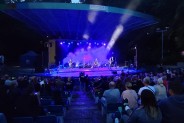 Ogólny plan Amfiteatru wieczorem. Scena rozjaśniona kolorowymi  światłami  i spowita w dymie. Na…