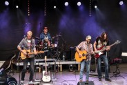 Na scenie amfiteatru pięcioro muzyków zespołu Alabama Band. Mają na sobie dżinsy i koszule w…