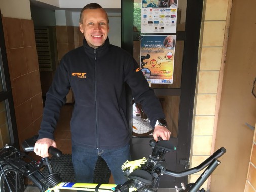Tomasz Dzierga stojący z rowerem w klatce bloku mieszkalnego