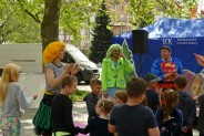 Aktorzy i aktorka tańczą z dziećmi podczas przedstawienia. z przodu dzieci oglądające spektakl. W…