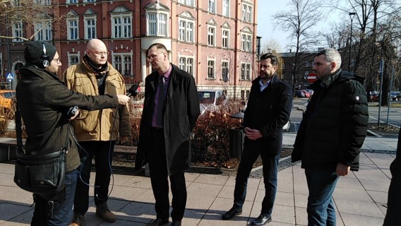 Dziennikarz z mikrofonem i uczestnicy konferencji
