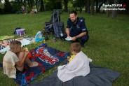 Policjant insruuje dzieci siedzące na kocu