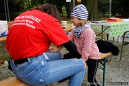 Wolontariuszka maluje dziewczynce na ręce podobiznę myszki Miki