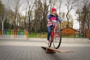 Dziewczynka przejeżdża rowerem przez tzw. pochylnię.