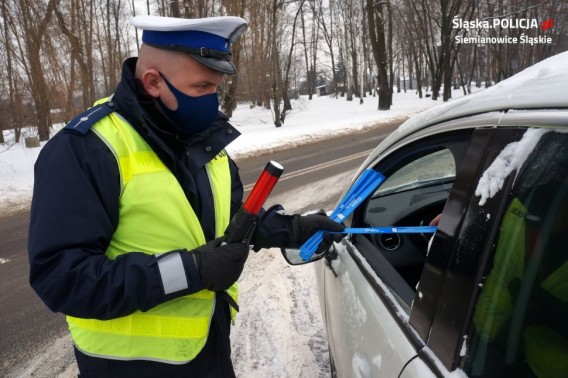 Policjant stojący przy samochodzie i rozmawiający z kierowcą